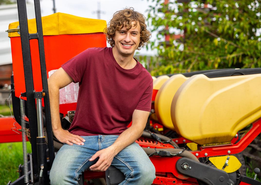 Jongeman zit op een trekker in de agrarische sector