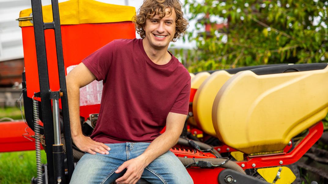 Jongeman zit op een trekker in de agrarische sector